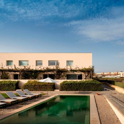 a swimming pool with lounge chairs and a building at Flattered to be in Algarve in Tavira