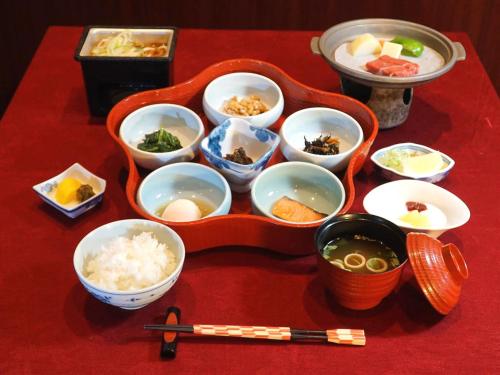 a red table with bowls of food and chopsticks at Arimakan in Kaminoyama