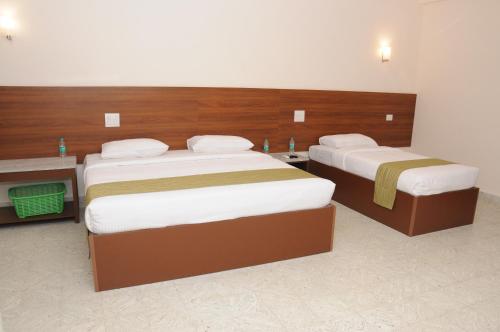 two beds in a hotel room with two at Sreeparthi Hotel in Puttaparthi