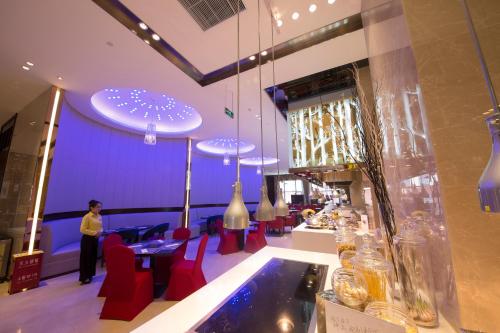 a restaurant with a bar with red chairs and purple walls at Novotel Daqing Haofang in Daqing
