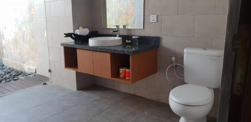 La salle de bains est pourvue de toilettes blanches et d'un lavabo. dans l'établissement Jimbaran Bay Villas, à Jimbaran