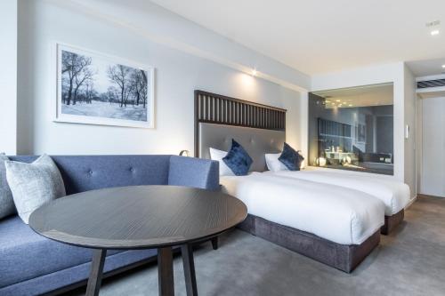 a hotel room with a bed and a table and a couch at The Vale Niseko in Kutchan