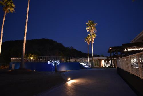 a pool with palm trees and a fountain at night at Alaise De Bale Shirahama in Shirahama