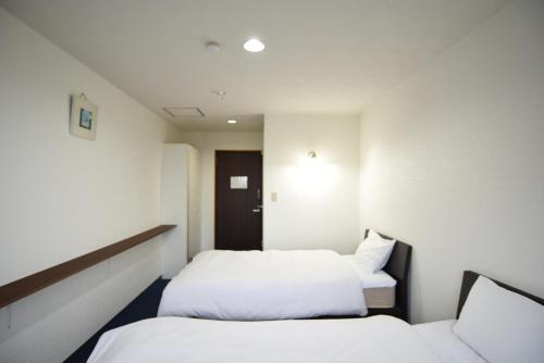 two beds in a room with white walls at Alaise De Bale Shirahama in Shirahama