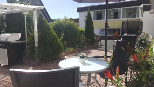 a patio with a table and chairs and an umbrella at Berghotel Natura Bed & Breakfast in Winterberg