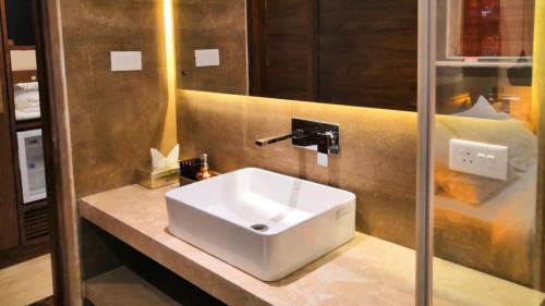 een badkamer met een witte wastafel en een spiegel bij Shivers Oasis Luxury Boutique Resort in Candolim