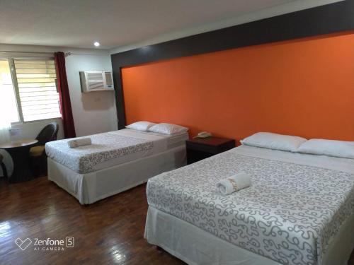two beds in a hotel room with an orange wall at Maharajah Hotel in Angeles