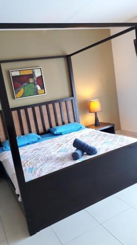 a large bed with a black frame and blue pillows at Gold Coast Morib Resort in Banting