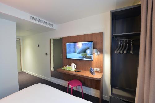 a bedroom with a bed and a tv on a wall at CAMPANILE PARIS - Clichy Centre in Clichy