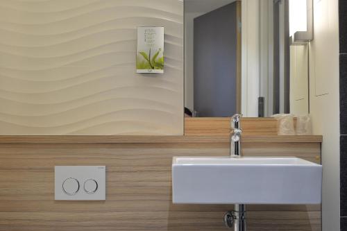 La salle de bains est pourvue d'un lavabo et d'un miroir. dans l'établissement CAMPANILE PARIS - Clichy Centre, à Clichy