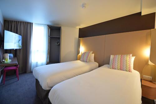 a hotel room with two beds and a television at CAMPANILE PARIS - Clichy Centre in Clichy