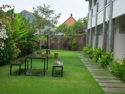 a garden with tables and benches in the grass at Adi Bali Homestay in Uluwatu
