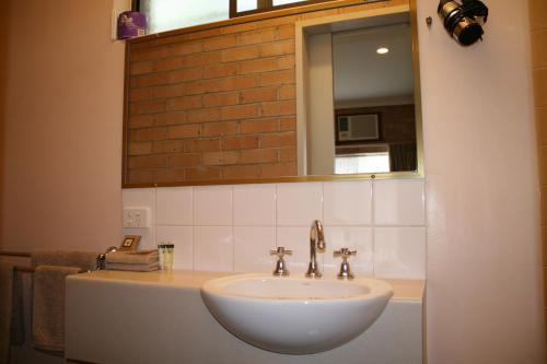 a white sink sitting under a mirror in a bathroom at Marriott Park Motel in Nowra