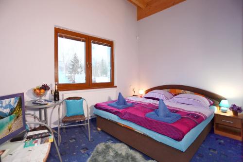 a bedroom with a bed with blue pillows and a desk at Pension Sunset Mezirolí in Nová Role