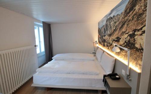 a hotel room with a bed and a painting on the wall at Hotel & Restaurant Forni in Airolo