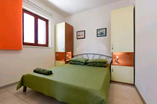 ein Schlafzimmer mit einem grünen Bett und einem Fenster in der Unterkunft Apartments Rena & Filip, by the beach in Preko