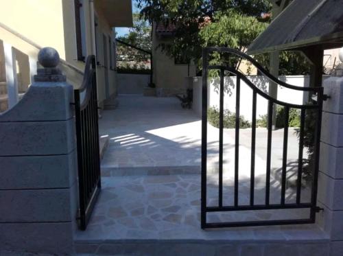 a wrought iron gate in front of a house at Apartments Rena & Filip, by the beach in Preko