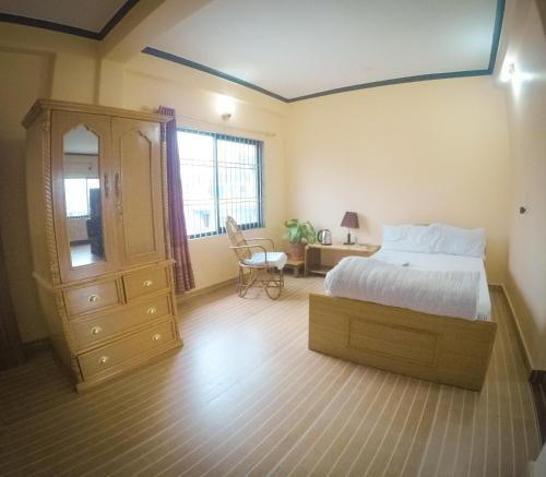 a bedroom with a bed and a dresser and a chair at Hotel Mountain View - Lakeside Pokhara in Pokhara