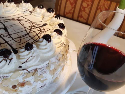 a cake with whipped cream and berries next to a glass of wine at Gasthof Klug zum Ehrensepp in Modriach