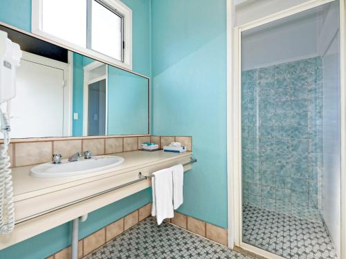 a bathroom with a sink and a shower at Riviera Motel Bundaberg in Bundaberg