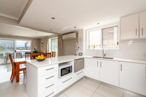a kitchen with white cabinets and a dining room at Saltwater Villas - Pet Friendly Accommodation in Mooloolaba