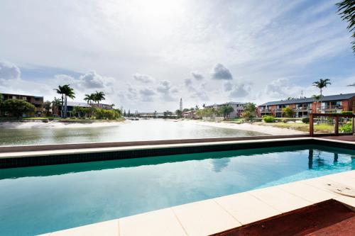a swimming pool next to a body of water at Saltwater Villas - Pet Friendly Accommodation in Mooloolaba