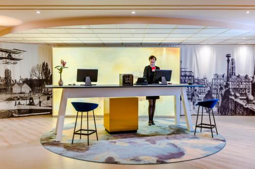 Eine Frau, die an einem Schreibtisch in einem Büro steht. in der Unterkunft Mercure Rouen Centre Cathédrale in Rouen