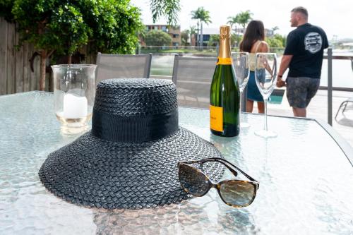 a hat and sunglasses sitting on a table with a bottle of wine at Saltwater Villas - Pet Friendly Accommodation in Mooloolaba