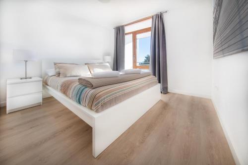 a white bedroom with a large bed and a window at Agaró Cambrils Apartments in Cambrils