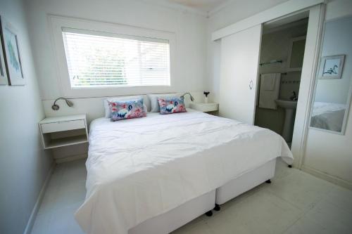 a white bedroom with a large white bed with pillows at Leisure By The Sea in Kleinmond