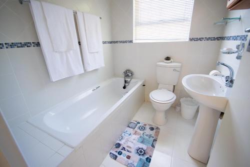 a bathroom with a tub and a toilet and a sink at Leisure By The Sea in Kleinmond