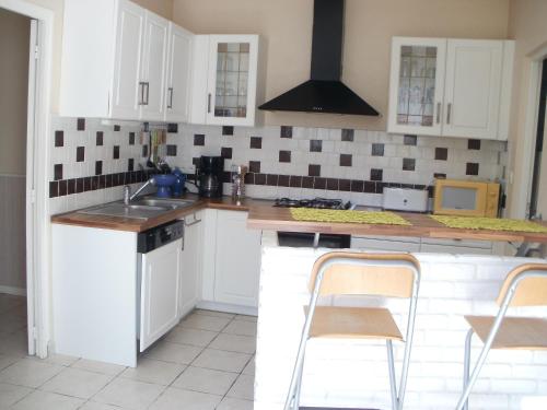 une cuisine avec des armoires blanches et un évier dans l'établissement Vacances a St Germain d Esteuil 33340, à Saint-Germain-dʼEsteuil