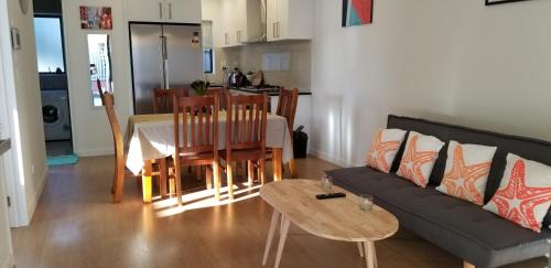 ein Wohnzimmer mit einem Sofa, einem Tisch und Stühlen in der Unterkunft New Smart Home Nearby Plaza in Auckland