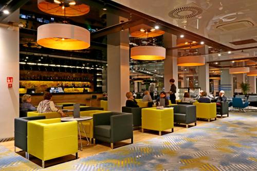 people sitting at tables in a restaurant with yellow chairs at Hotel Hamilton SPA & Wellness in Świnoujście