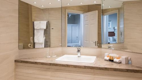 a bathroom with a sink and a large mirror at The Victoria Hotel in Sidmouth