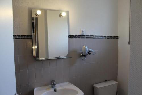 a bathroom with a sink and a mirror and a toilet at Villa Hotel in Troyes