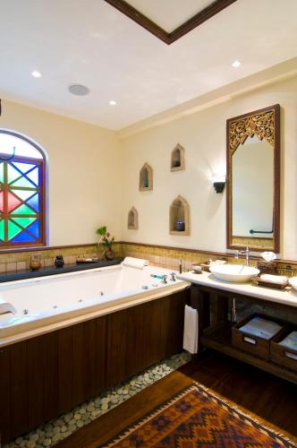 a large bathroom with a large tub and a stained glass window at Ariyasom Villa in Bangkok