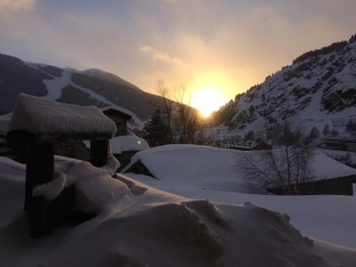 a snow covered mountain with the sun setting in the background at Hotel Roc de St Miquel & Apartment in Soldeu