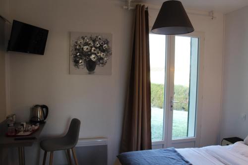 een slaapkamer met een bed en een raam met een vaas met bloemen bij Villa Hotel in Saint-André-les-Vergers