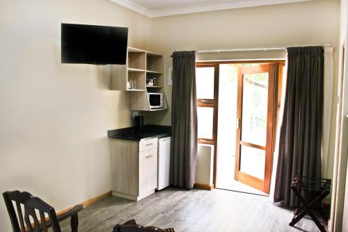 a room with a kitchen with a microwave and a window at 17 on Bird Guest House in Beaufort West