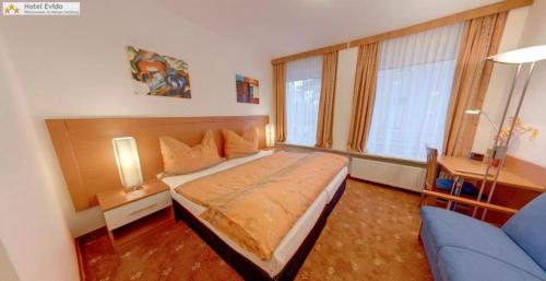 1 dormitorio con 1 cama y 1 sofá azul en Evido Rooms, en Salzburgo