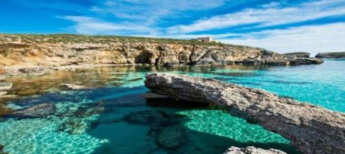 a beach with clear blue water and a rocky shore at Villa Naxxar Malta in Naxxar