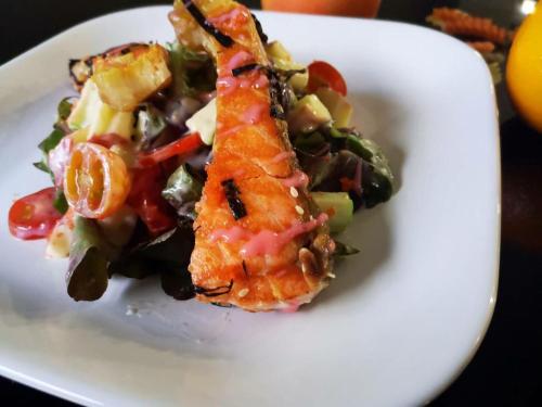 a white plate with a piece of fish and vegetables at The Harbour Front Hotel in Suratthani