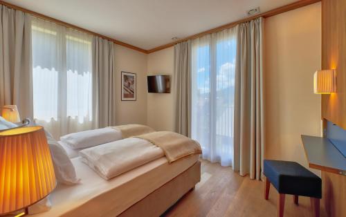 a bedroom with a bed and a large window at Residence Zur Post Sexten in Sesto