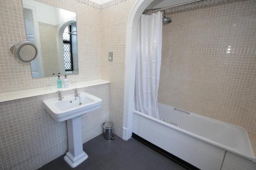 La salle de bains blanche est pourvue d'un lavabo et d'une douche. dans l'établissement Rothley Court Hotel by Greene King Inns, à Rothley