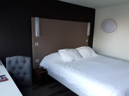 - une chambre avec un grand lit blanc et une chaise dans l'établissement Campanile Sablé-Sur-Sarthe Vion, à Sablé-sur-Sarthe
