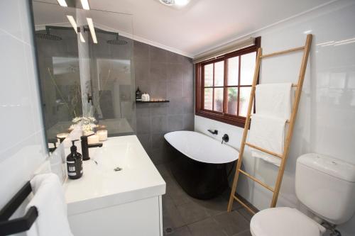 a white bathroom with a sink and a toilet at Wayfarers Cottage in Goolwa