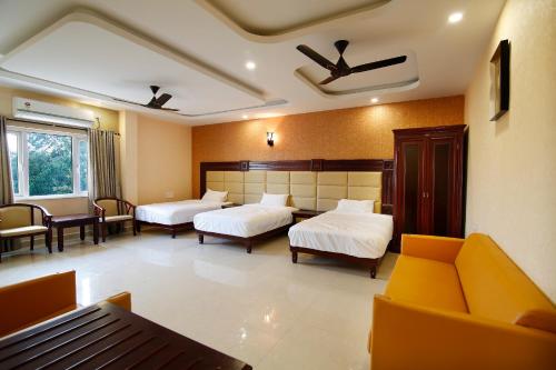 una habitación de hotel con dos camas y un sofá en RB GRAND RESIDENCY, en Kanchipuram