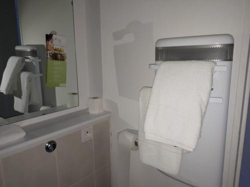 a bathroom with a towel dispenser and a mirror at Campanile Sablé-Sur-Sarthe Vion in Sablé-sur-Sarthe