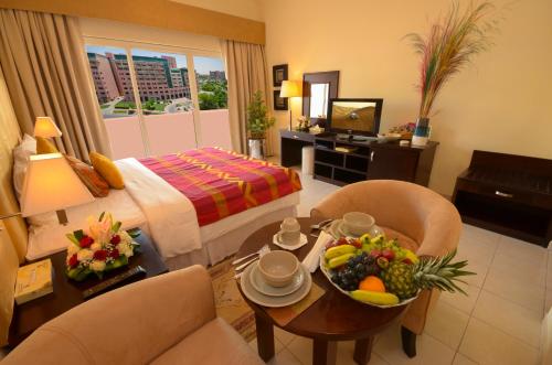 a hotel room with a bed and a table with a bowl of fruit at Parkside Hotel Apartment in Dubai